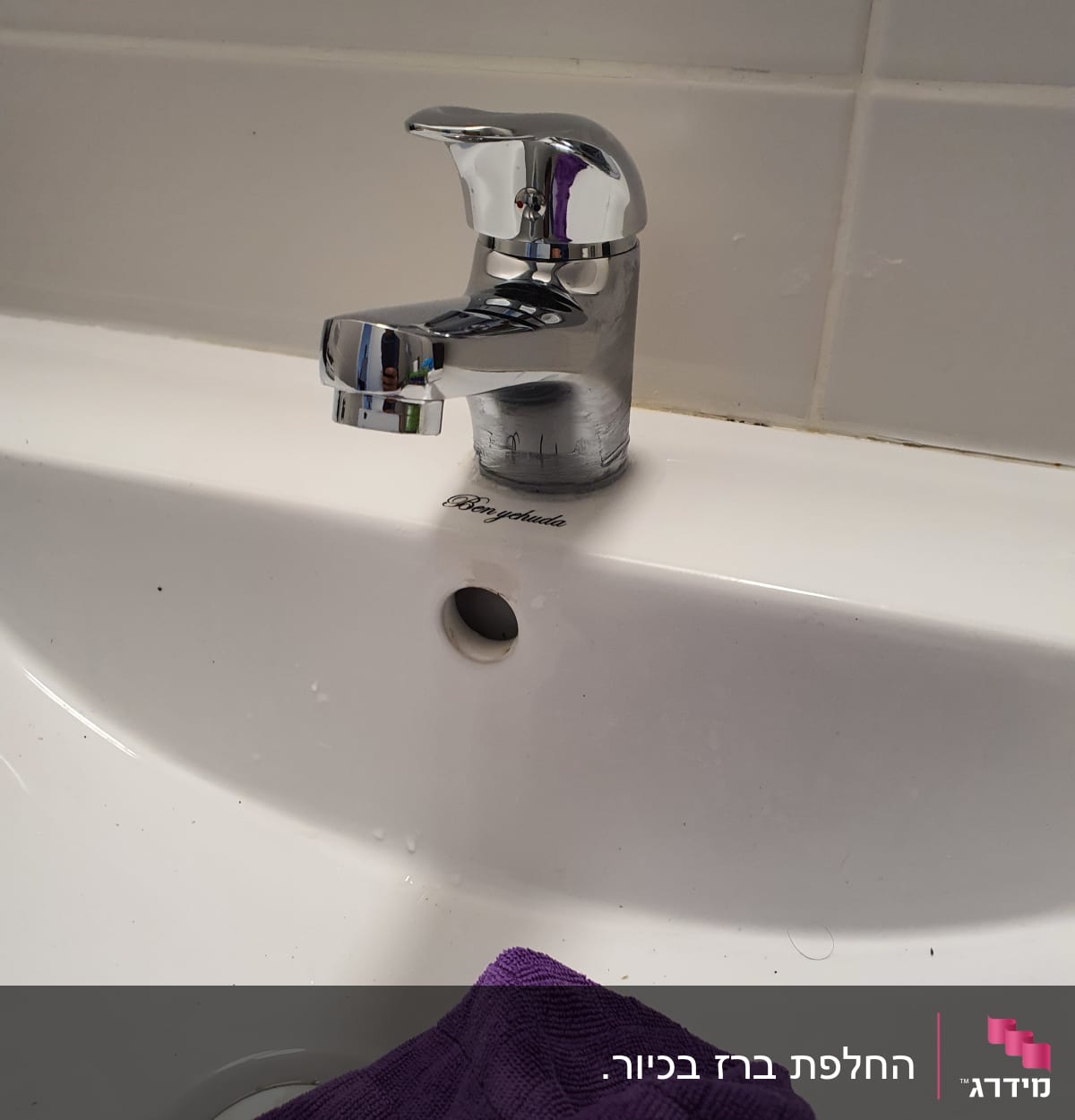 ברז כרום על כיור לבן עם מטלית סגולה